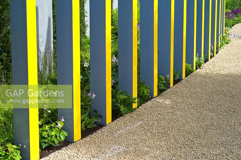Garden feature of painted upright pergola columns lining a gravel path RHS Hampton Court Palace Flower Show