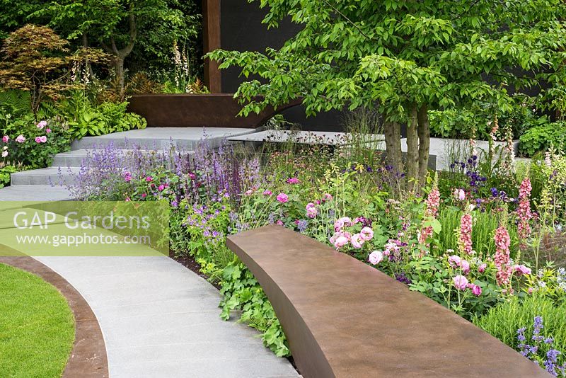 Curving path, seat and borders in The Chelsea Barracks Garden at the RHS Chelsea Flower Show 2016. Designer: Jo Thompson.