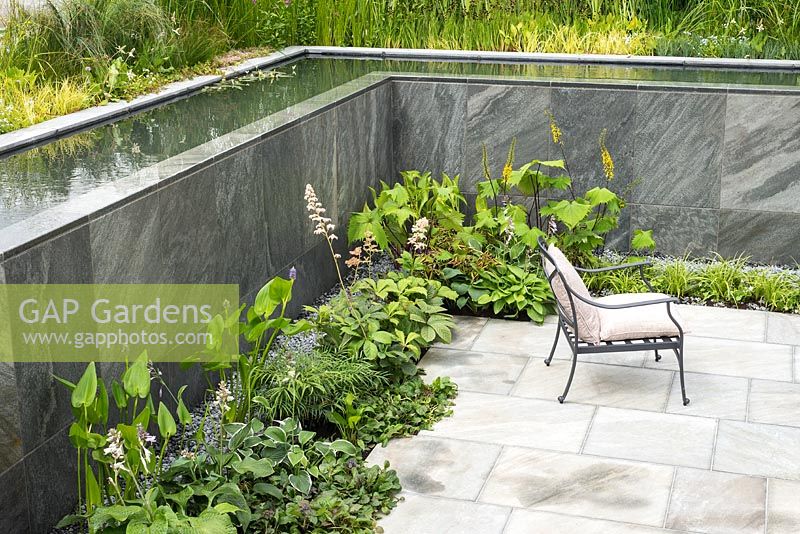 Paved sunken garden with flowing water pool, cascading water walls and seating
