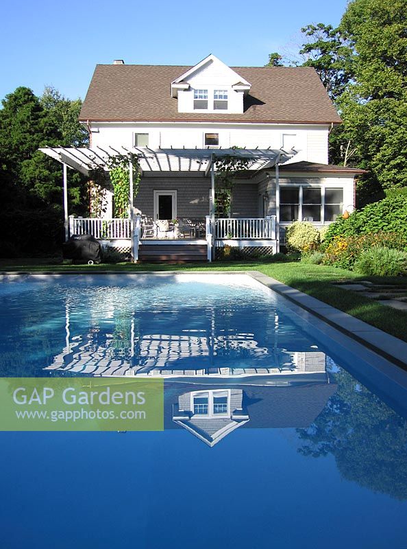 House with verandah with white painted furniture looking to swimming pool in the Hamptons Long Island USA