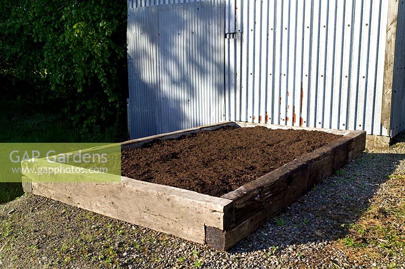 Newly completed raised bed for vegetables made from old railway sleepers and filled with compost