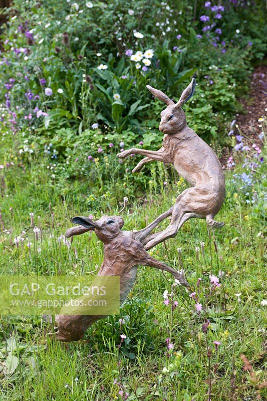 The Skyshades Garden - Powered by Light designed by Marney Hall. Sculpture of two hares boxing amongst meadow flowers.s