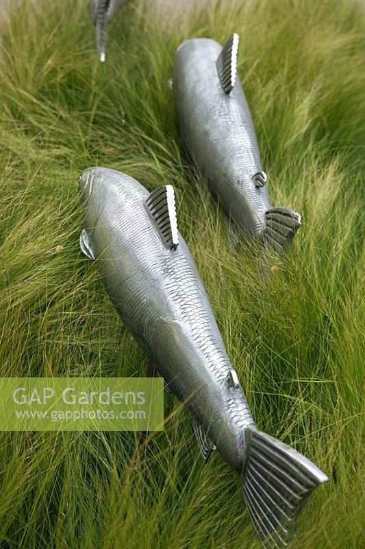 Metal fish in border of Stipa tennuissima on the Gaze Burvill stand at RHS Chelsea Flower Show 2012