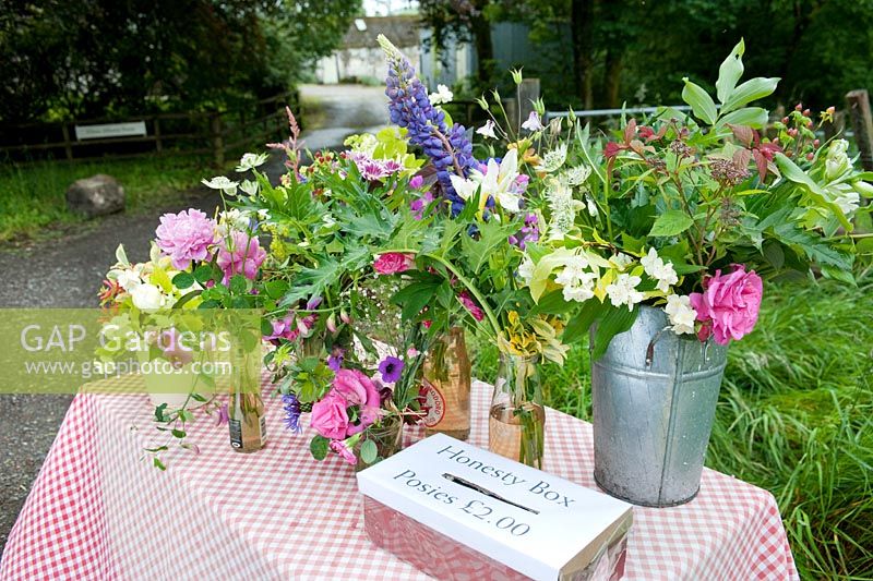 Posies of colourful cut flowers for sale on a roadside table with honesty  box