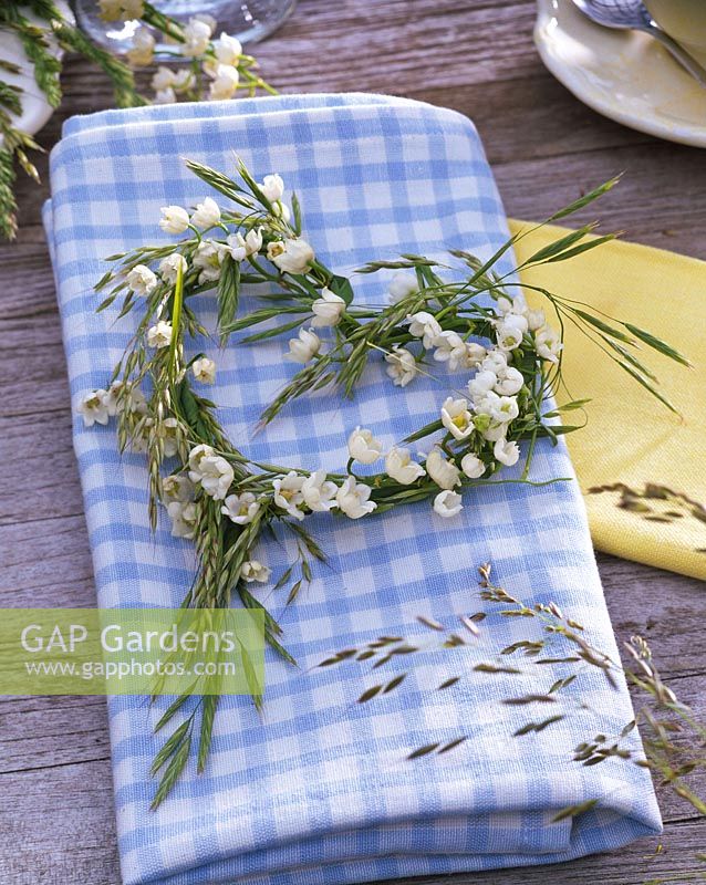 Wreath of Convallaria ( lily of the valley ) and grasses in heart shape on napkin