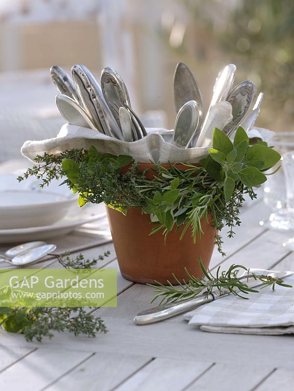 Garland of herbs to clay pot with cutlery