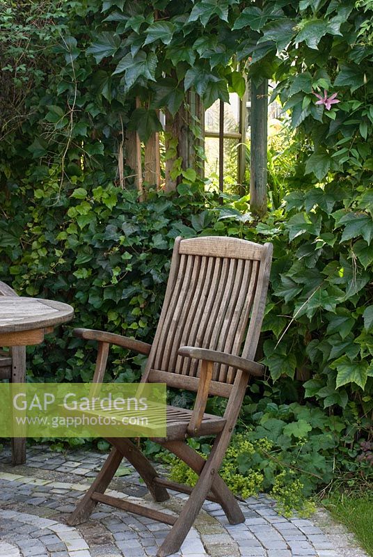 Wooden chair on a small, paved terrace in front of Garden House