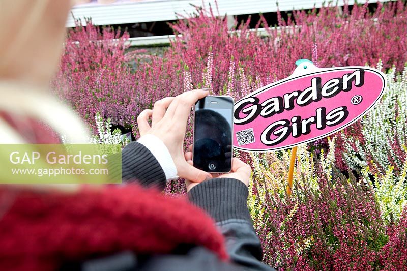 Young woman in the garden center scanning the QR code