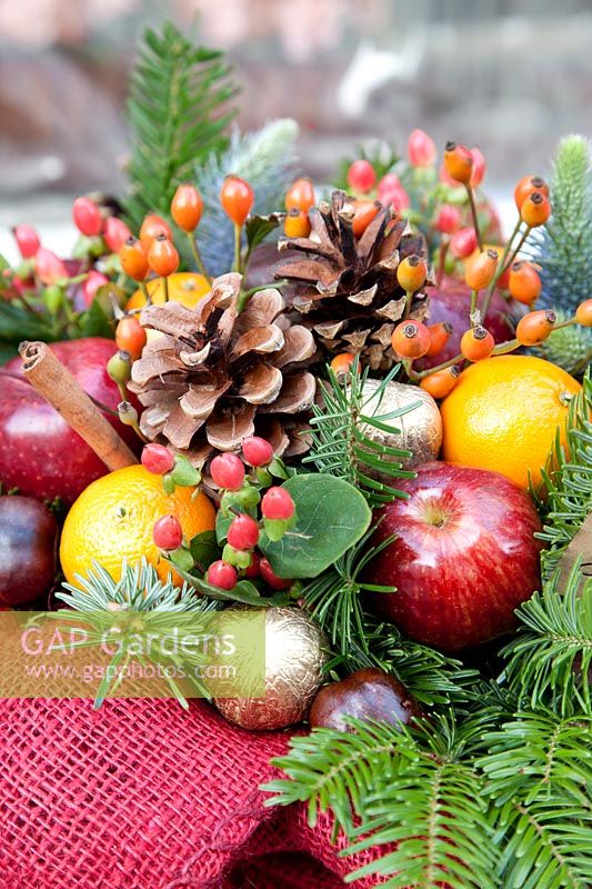 Christmas arrangement with Hypericum, brushwood, oranges, cones and apples