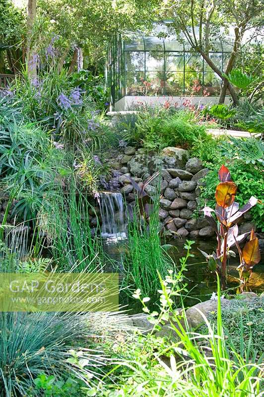 Tropical garden with waterfall and greenhouse