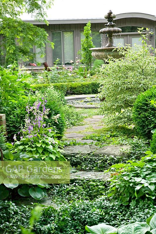 View into the garden with water fountain, different perennials and shrubs