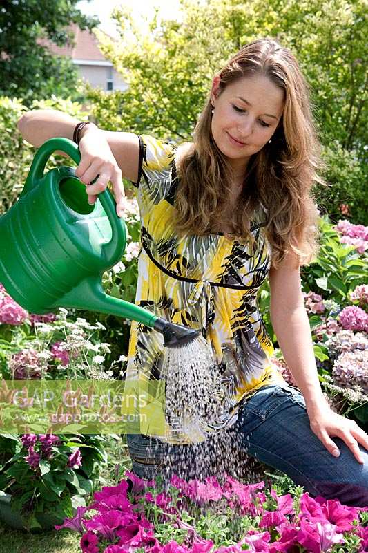 Girl watering summerflowers in the garden