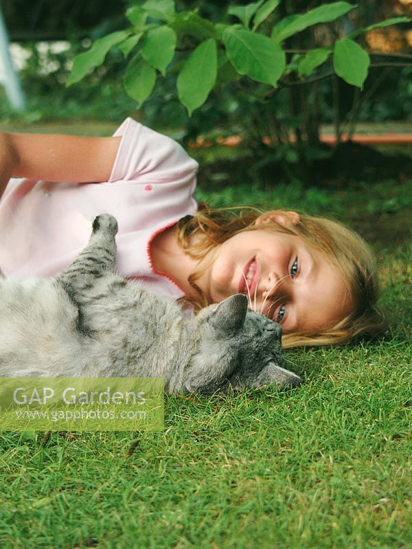 Girl with cat in the garden lies on the grass
