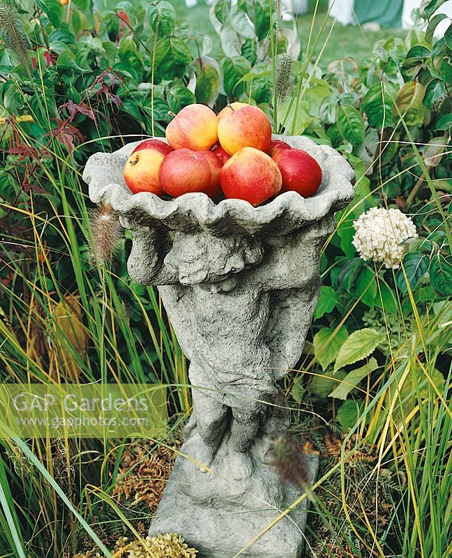 Stone sculpture with apples in autumn
