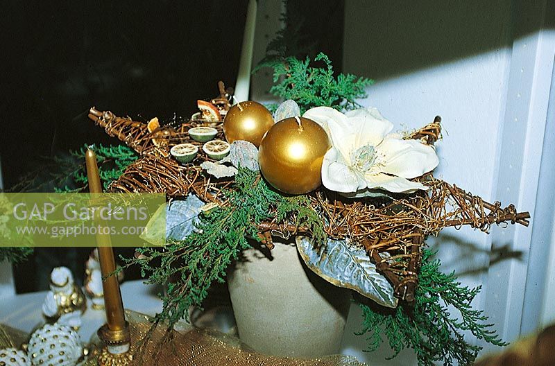Adventsgesteck mit goldenen runden Kerzen und weisser Blüte