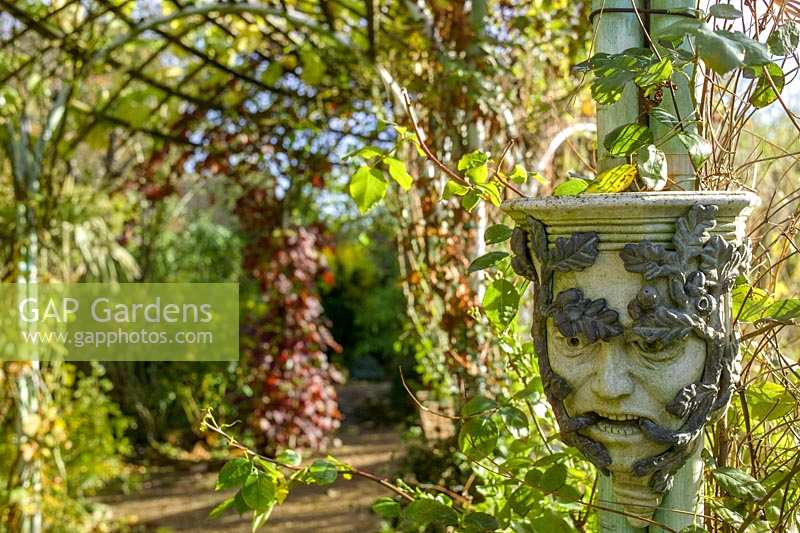 The Abbey House, Malmesbury, Wiltshire, UK ( Pollard ). Autumn in large garden, 'Pagan' masks as ornament