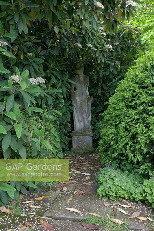Barnsley House Gardens, Glos., UK. Former garden of Rosemary Verey, statues hidden amongst bushes at edge of garden