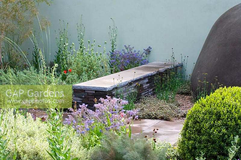 Chelsea Flower Show 2006, London, UK. 'The Saga Insurance garden' ( des. Cleve West ) low stone bench in informal herb garden