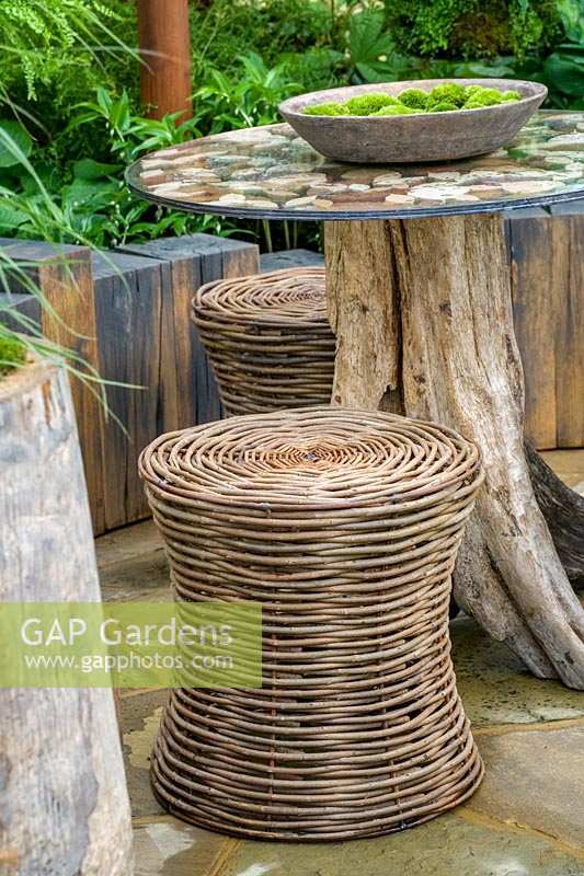 Chelsea Flower Show 2006, London, UK. 'The Green Room' ( des. Caspar Gadd ) basketwork chairs and small table in patio garden