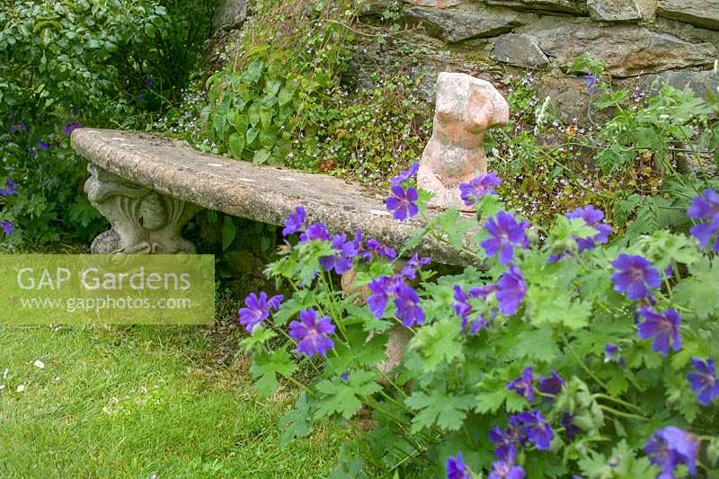 stone bench in garden with sculpture of torso