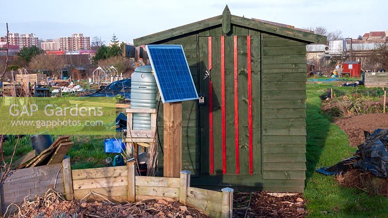 Garden shed on allotment with solar panel to power rabbit proof fence
