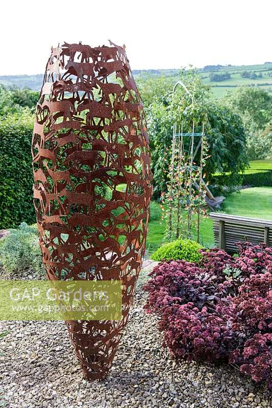 Derry Watkins Garden at Special Plants, Bath, UK with modern metal sculptural pot, 'Vessel' by David Mayne