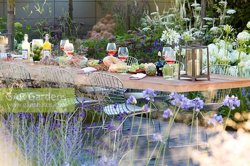 Hampton Court Flower Show 2014, the Vestra Wealth Garden, des. Paul Martin. Modern table and chairs set for a light lunch outdoors