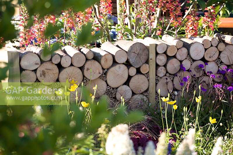 Hampton Court Flower Show 2014, the Hampton Garden, des. Ian Hammond. Low cut log wall in summer garden