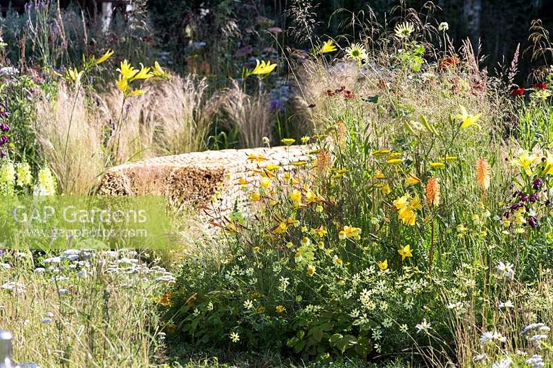 Hampton Court Flower Show 2014, the Jordans Garden, des. Selina Botham. straw bench amongst naturalistic grasses and perennials