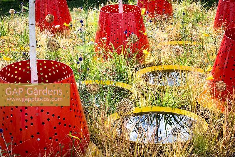 Hampton Court Flower Show, 2017. Kinetica Garden, des. Senseless Acts of Beauty, red planters with Betula jacquemontii above small circular ponds.