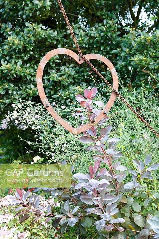 Little Ash Garden, Fenny Bridge, Devon. Autumn garden. Metal heart shaped sculpture