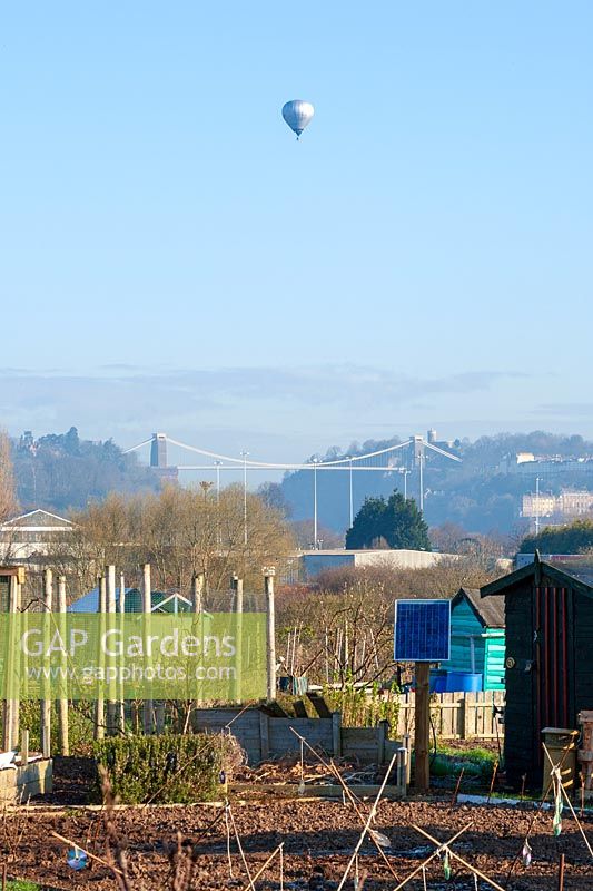 Hot air balloon flying over Clifton Suspension Bridge and allotments