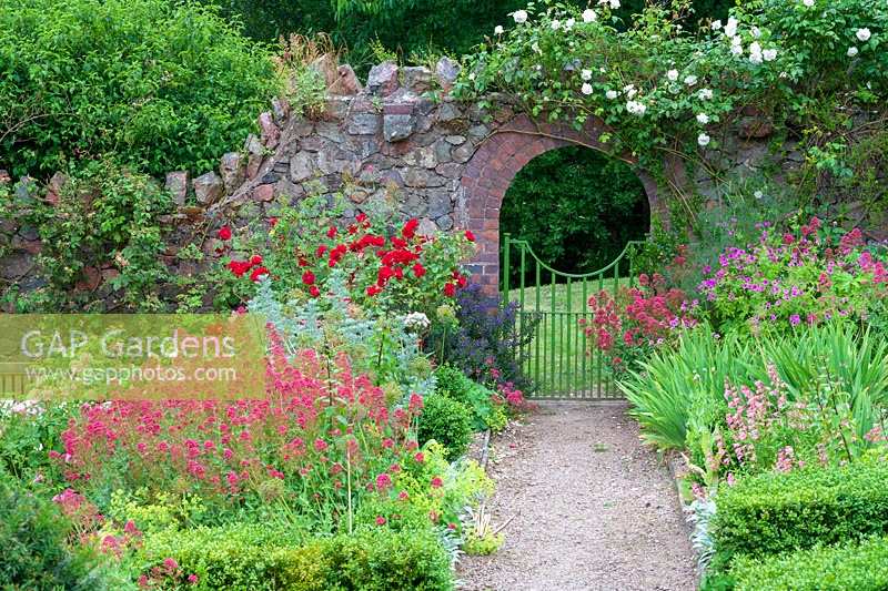 Perrycroft, Herefordshire. ( Archer ) informal summer borders with Valerian and Roses, view through gateway,( PR available )