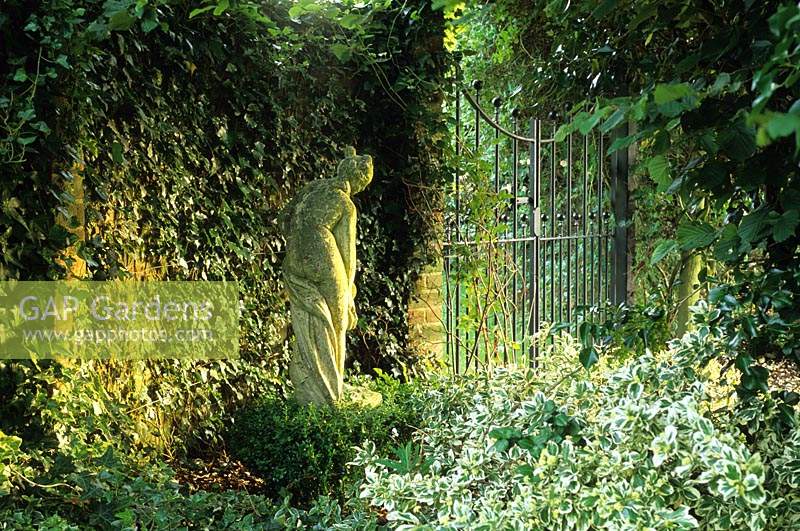 Private garden Surrey classical statue beside walled garden gate.