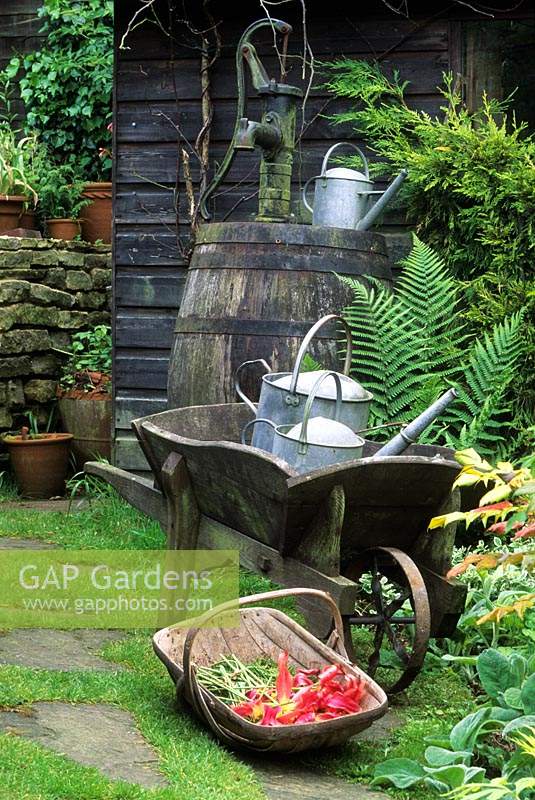 Alan Titchmarsh garden Hampshire wooden wheelbarrow with watering cans and trug with cut tulips