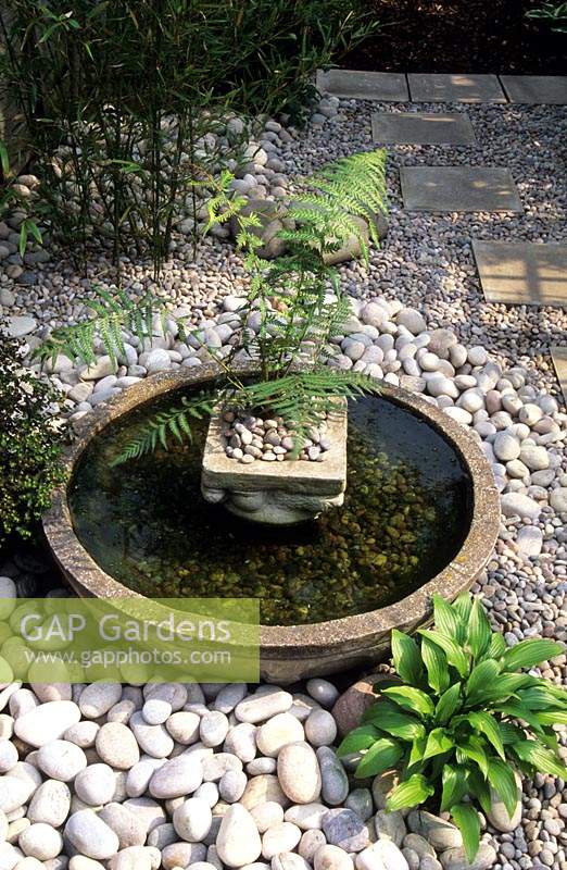 shallow bowl water feature Japanes style in small town garden surrounded with attractive white stone and pebble mulch