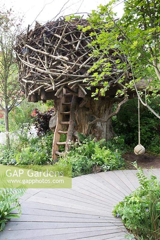 The RHS Back to Nature Garden  – tree house made from wood and tree branches, wooden ladder made from tree slab, rope swing, wooden decking board walk, planting of ferns and shade loving plants - Designer: HRH The Duchess of Cambridge with Andree Davies and Adam White - Sponsor: The RHS 
