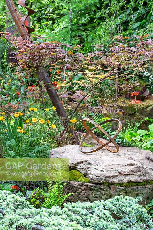 Sculpture made of two rusty metal rings. Walker's Forgotten Quarry Garden - Designer: Graham Bodle - Sponsor: Walker's Nurseries