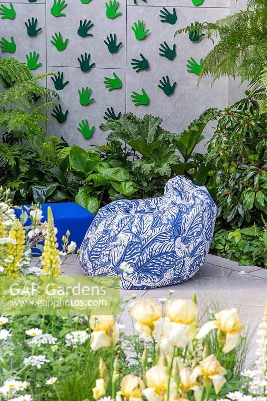 Patterned bean bag in modern garden, surrounded by lush planting. The Greenfingers Charity Garden. Designed by Kate Gould Gardens, sponsored by Greenfingers Charity, RHS Chelsea Flower Show, 2019.
