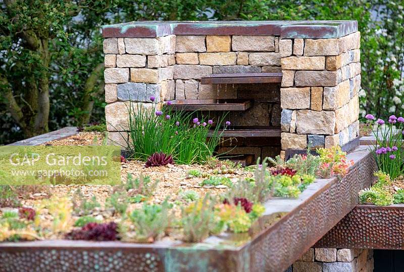 The Warners Distillery Garden,  view of the living roof with Allium schoenoprasum, various Sedums and Thymus with dry stone chimney and water feature of Copper fins designed by Andy Ewinź- Design: Helen Elks-Smith - Construction: Bowles and Wyer - Sponsor: Warners Gin.
