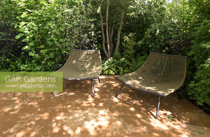The M and G Garden, view of green garden planted with shade loving plants in a woodland garden, English ironstone paving patio, garden furniture chairs – Designer: - Sponsor: M and G 