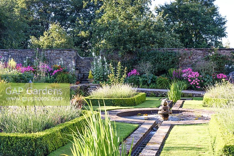 Formal rill and circular pond with box edged beds of lavender, July.