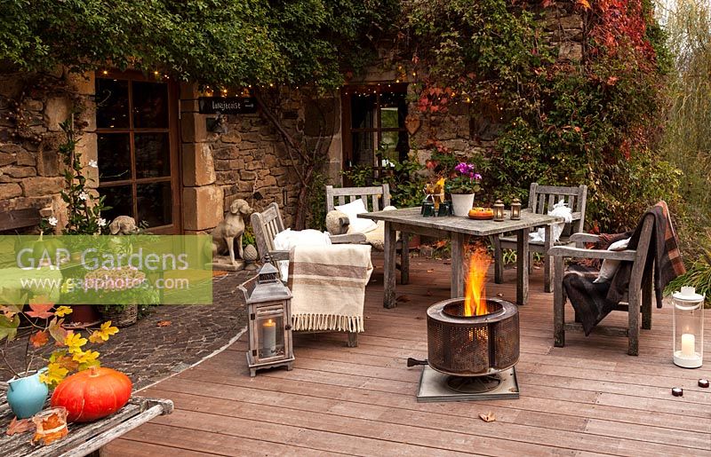Garden table, chairs and fire basket on garden terrace for evening entertaining, Le Mas de BÃ©ty, France.