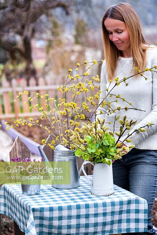 Woman making floral arrangements with catkins, heathers, Cornelian Cherry  and hellebores.