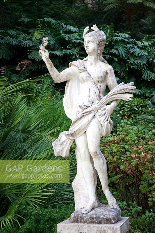 Statue of Demeter - Ceres  - on The Promenade of The Gods surrounded by  Chamaerops Humilis and Monstera deliciosa - Swiss Cheese Plant. Sintra, Portugal.