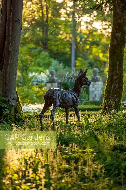 Sculpture of roe deer by Hamish Mackie under trees at  Ablington Manor, Gloucestershire. 
