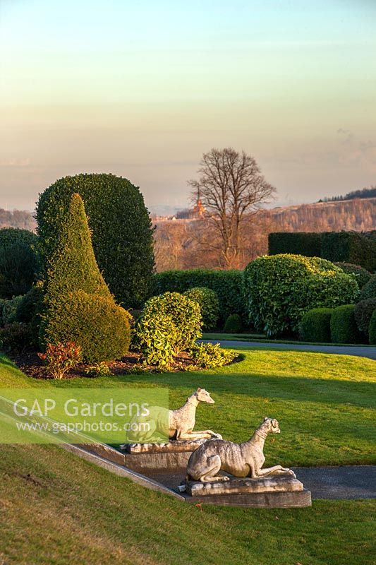 A view of the lawns and formal topiary gardens at Brodsworth Hall, Yorkshire at dusk.
