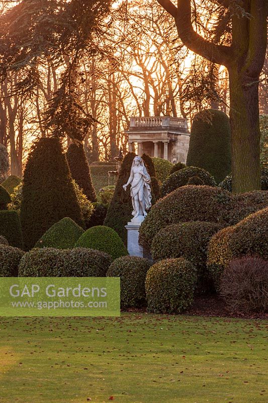 A garden statue among clipped topiary hedging at dusk, Brodsworth Hall, Yorkshire. 