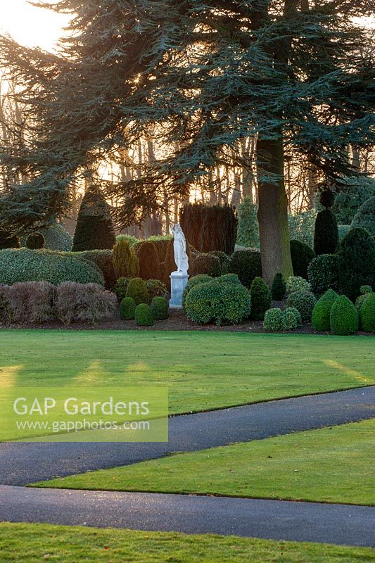 A formal topiary border and white statue at Brodsworth Hall, Yorkshire.
