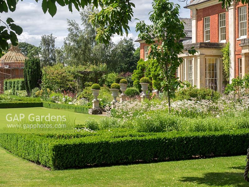Formal garden featuring Buxus sempervirens hedging and topiary balls planted in urns at Newport House, Herefordshire.

